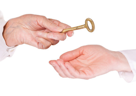 Old woman handing keys to younger womanの写真素材