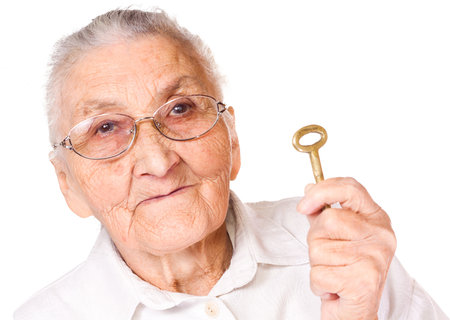 Old woman with isolated background, holding keyの写真素材