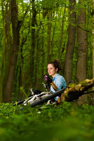 young, beautiful woman sitting with bicycleの写真素材