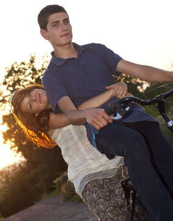 Young  couple riding a bicycle in a park の写真素材