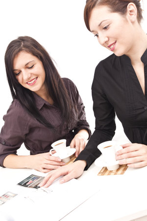 Two friends having coffee and reading a magazineの写真素材