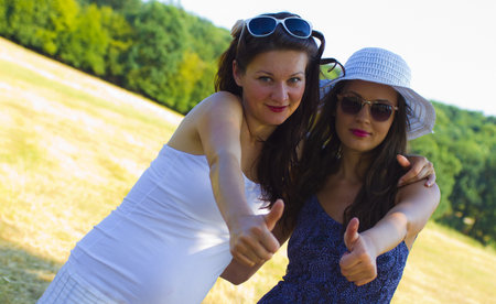 Two girls thumbs up in the parkの写真素材