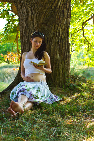 Pregnant attractive woman reading in parkの写真素材