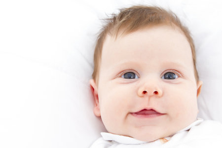 portrait of a cute little baby lying ona  white bedの写真素材