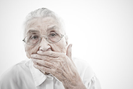 portrait of a very old woman  who is masking her mouth with her handの写真素材