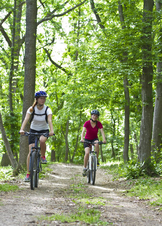 two girls riding the bicycle in the forestの写真素材