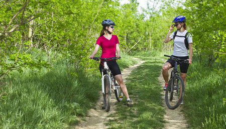 two girls riding the bicycle in the forestの写真素材