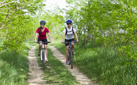 two girls riding the bicycle in the forestの写真素材