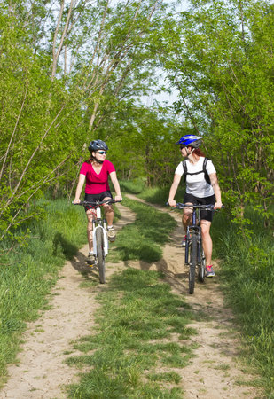 two girls riding the bicycle in the forestの写真素材