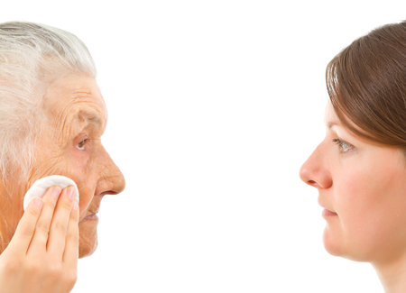 young woman wiping off an  old woman's face  with a make up padの写真素材