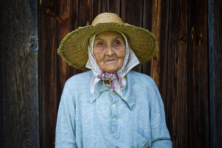 very old woman from village  in front of a wooden  backgroundの写真素材