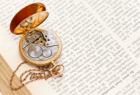 vintage gold pocket watch lying on a book