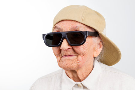 Funny grandma's studio portrait  wearing eyeglasses and baseball cap, isolated on whiteの写真素材