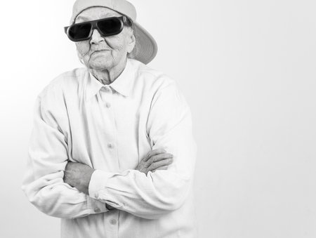 Funny grandma's studio portrait  wearing eyeglasses and baseball cap, who stands for her right,  in balck and whiteの写真素材