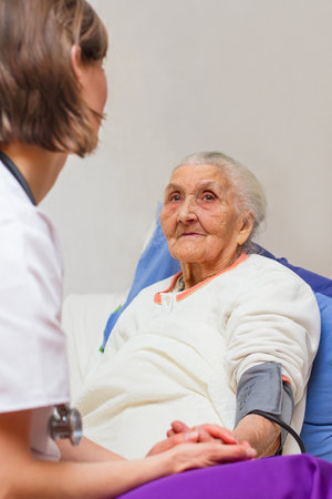 Happy joyful nurse caring for an elderly woman helping her days in nursing home.の写真素材