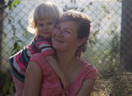 adorable toddler girl with her mother in haystackの写真素材