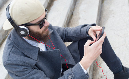 Handsome guy listening to music with heatset in his mobile.