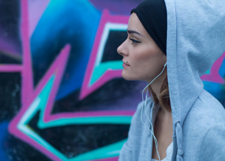 Beautiful street girl in the ghetto next to a graffiti wall.