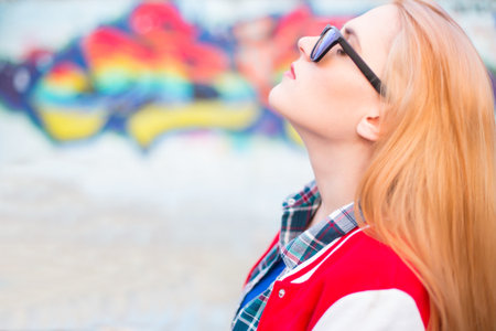 Beautiful blond woman relaxing against a graffiti wall.