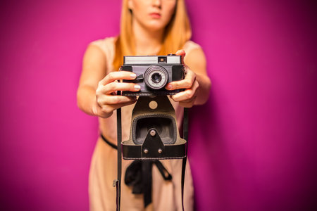 Female photographer holding an old camera - purple background.の写真素材