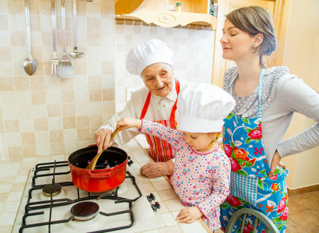 Grandmother teaching grand-daughter how to cook.の写真素材