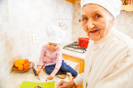 Elderly lady teaching little girl how to cook the best dishes.の写真素材