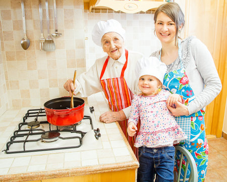 Grandmother cooking with daughter and grand-daughter in the kitchen.の写真素材