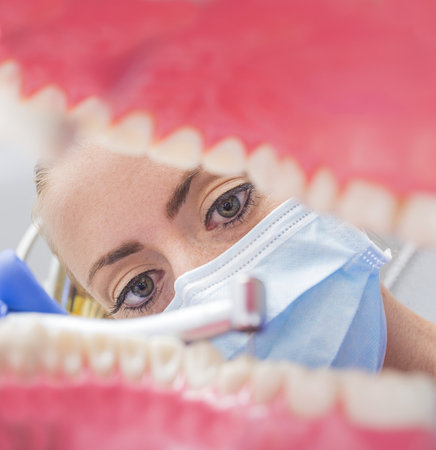 Dentist in mask drilling and cleaning teeth.の写真素材