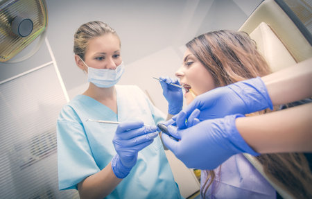 Careful dentist helped by assistant making satisfying dental treatment together.の写真素材