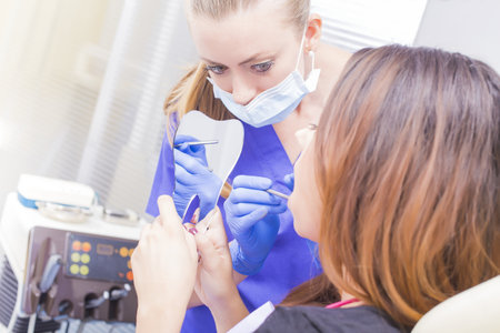 Doctor explaining patient some tooth problems- checking in mirror.の写真素材
