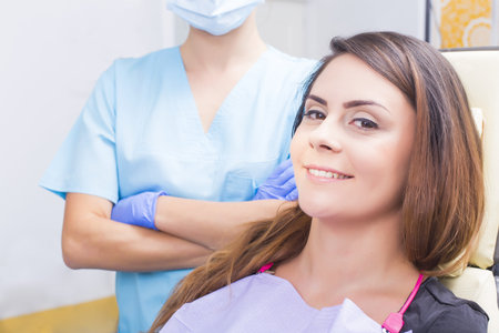 Beautiful woman smiling in the dental chair - doctor behind.の写真素材