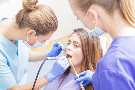 Dentist filling woman's teeth and assistant helping out.の写真素材