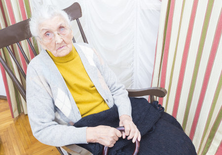 Kind elderly lady in a nursing home sitting on a chair.の写真素材