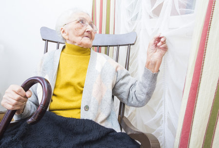 Kind elderly lady in a nursing home waiting for family to arrive.の写真素材