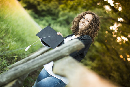 happy graduate girl with a hat in her handsの写真素材
