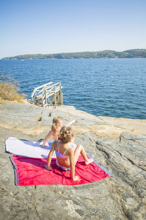 Children relaxin on towels on the beachの写真素材