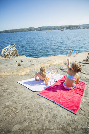 Children relaxin on towels on the beachの写真素材