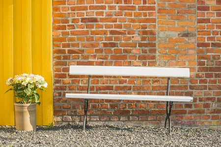 white bench in front of a brick wallの写真素材