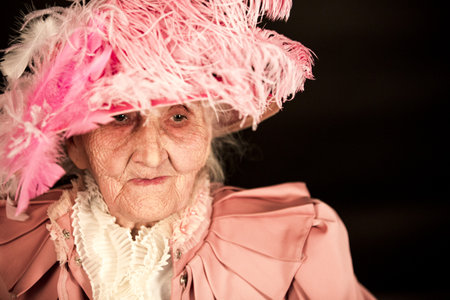 Old stylish lady in mauve jacket and a hatの写真素材
