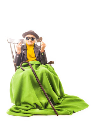 Old woman with sunglasses sitting on a chair.の写真素材
