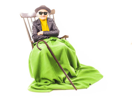 Old woman with sunglasses sitting on a chair.の写真素材