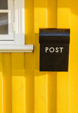 yellow wooden wall with a black letterboxの写真素材