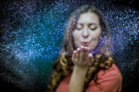 Colorful glitter blown by a young girlの写真素材