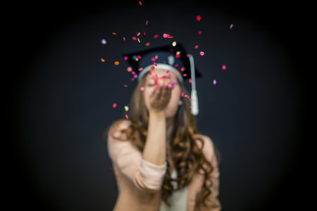 Confetti girl with graduation hat and black backgroundの写真素材