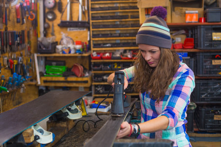 Pretty girl repairing ski in the workshopの写真素材