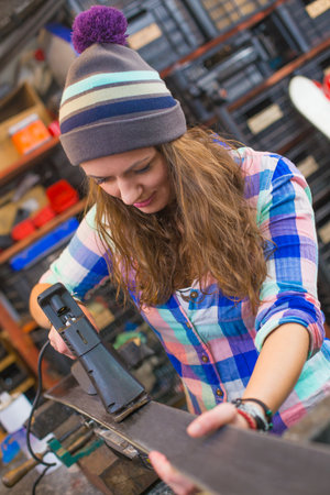 Pretty girl repairing ski in the workshop