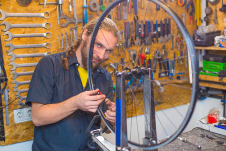 Blue eyed guy repairing bicycle in the workshopの写真素材