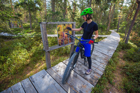 gorgeous woman standing with a bicycle in the wooden forest pathの写真素材
