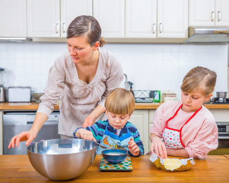 Happy family moments as a mother teaches her children the joy of baking together.の写真素材