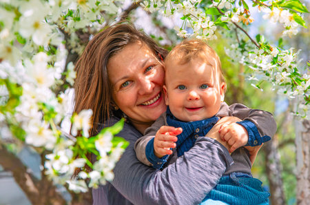 Mother and baby enjoying bonding time in nature surrounded by beautiful blooming flowers.